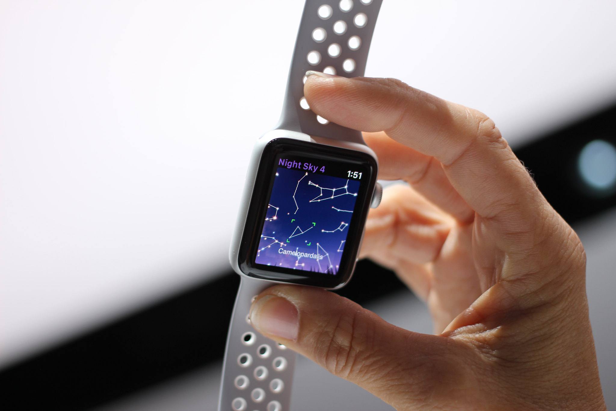 Mão segurando um Nike Apple Watch com Night Sky 4 na tela