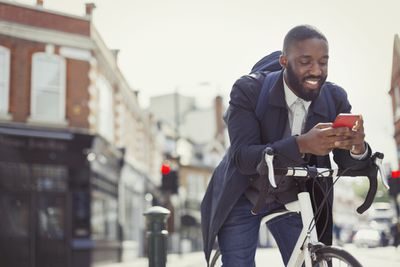 Empresário de bicicleta enviando e-mail com celular