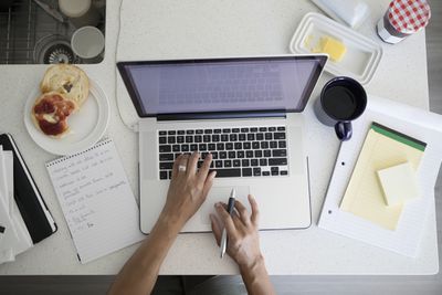 Foto de mulher digitando em um laptop cercada por blocos de notas
