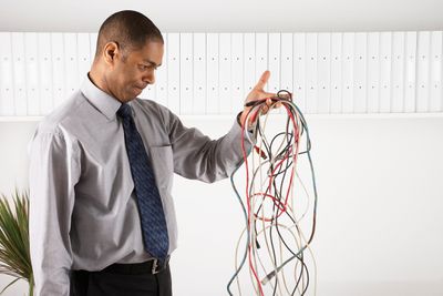 Empresário examinando um emaranhado de cabos eletrônicos