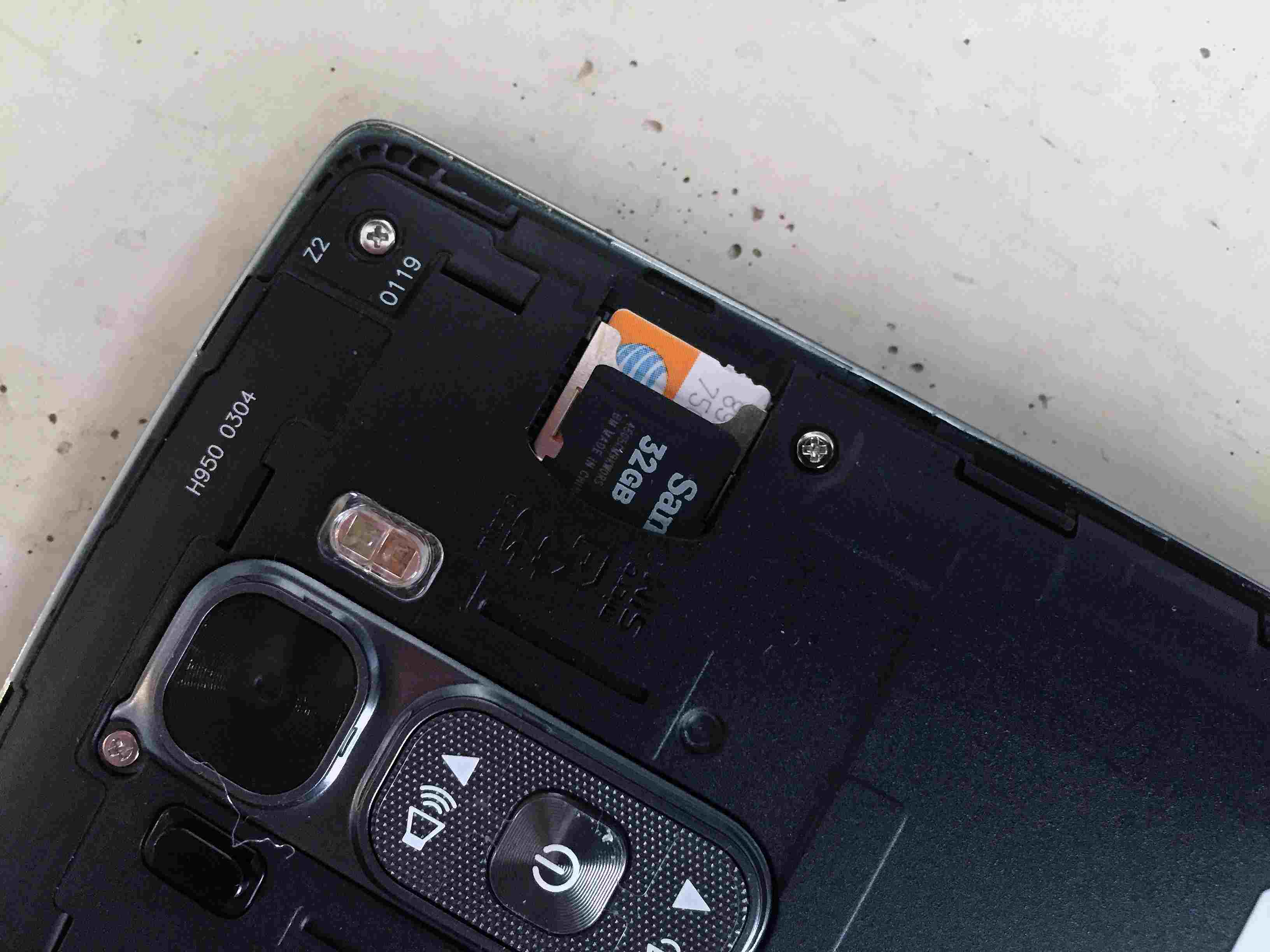 Parte traseira do telefone aberto encontrando o slot microSD no LG G Flex 2