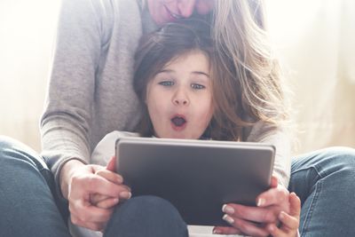 Uma criança sentada com seus pais e usando um iPad.