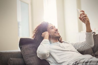 Homem relaxando no sofá usando o facetime em um iPod com fones de ouvido