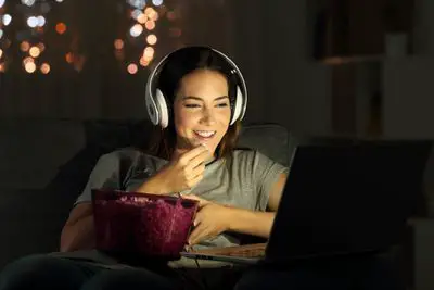 Mulher com fones de ouvido assistindo a um filme no laptop