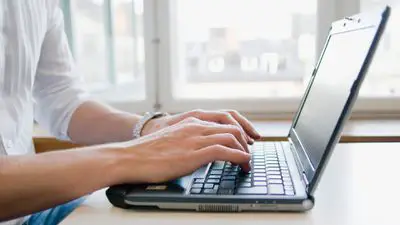A man using Windows 10 keyboard shortcuts on a laptop computer.