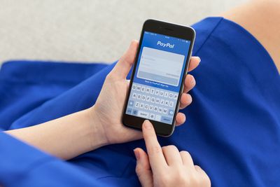 Um telefone com a tela de login do PayPal exibida.
