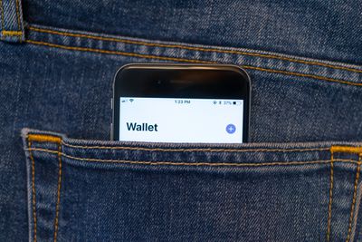O aplicativo Apple Wallet em um iPhone saindo do bolso de alguns jeans