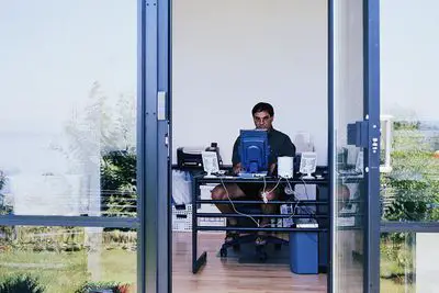 Homem sentado em frente ao computador em um pequeno escritório