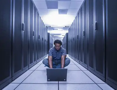 Homem usando o computador na passagem entre os servidores