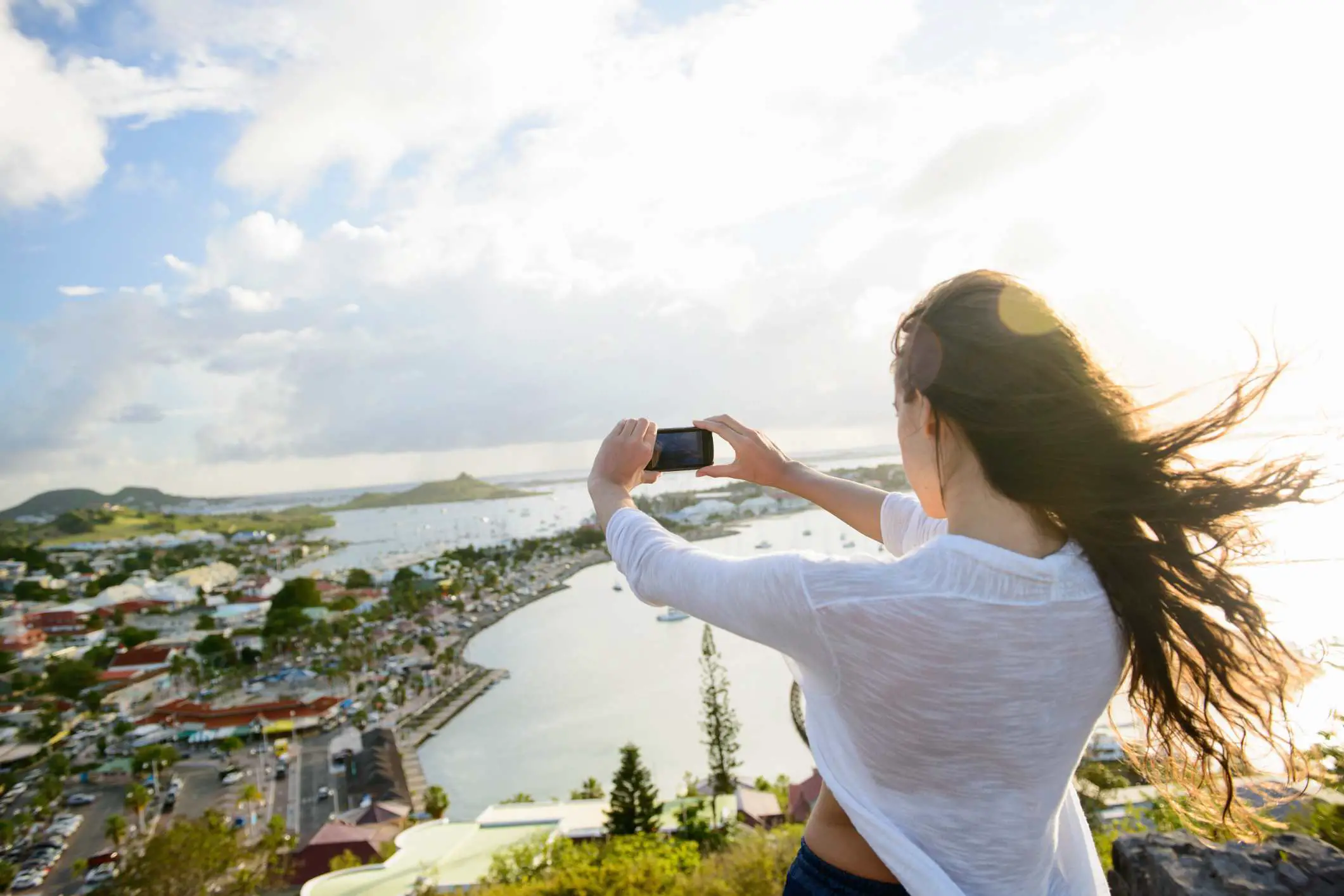 Pessoa tirando uma selfie no topo de uma colina perto de uma baía