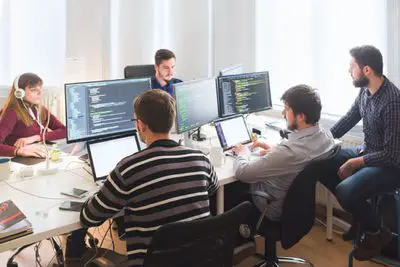 Equipe de desenvolvimento de software trabalhando no escritório com grandes monitores