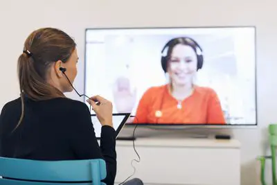 Imagem de uma mulher tendo uma videoconferência em uma televisão