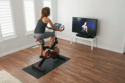 Pessoa transmitindo iPad da bicicleta ergométrica para a TV