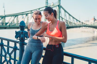 Duas mulheres corredoras descansando, olhando para seus rastreadores de fitness