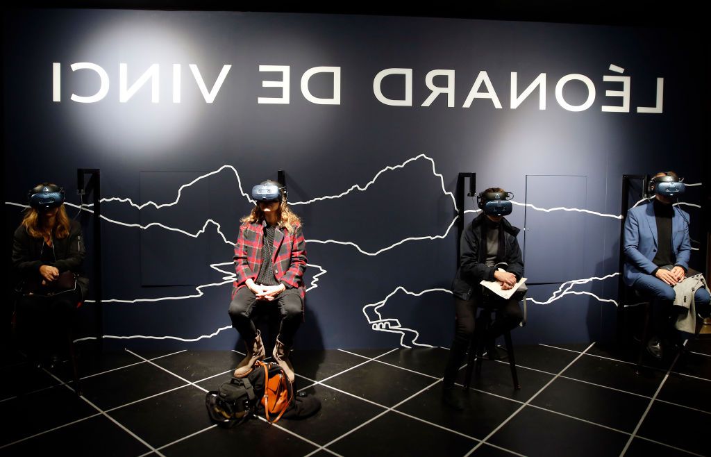 Os visitantes usam um fone de ouvido de realidade virtual (VR), enquanto assistem a animações virtuais e interativas, durante uma visita de imprensa à exposição "Leonardo da Vinci" no museu do Louvre.