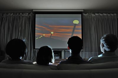 Família assistindo filme em casa na tela de projeção