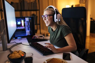 Uma mulher sorrindo para uma mesa olhando para a tela de um monitor de PC