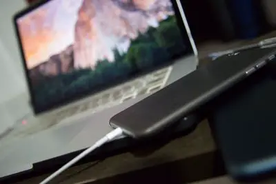 Um iPhone é conectado por USB a um laptop Mac.