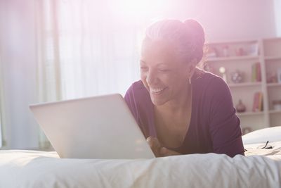 Mulher usando laptop na cama
