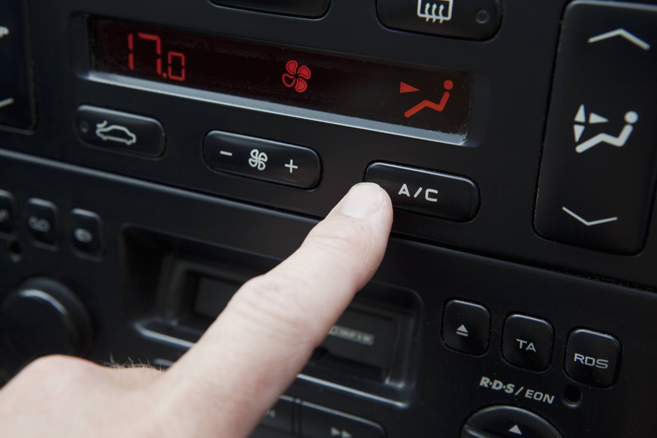 Mão pressionando o botão AC no carro