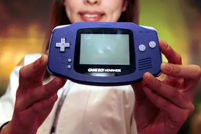 Uma mulher segurando um Game Boy Advance.