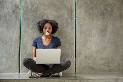 Estudante universitário afro-americano usando laptop e soprando chiclete