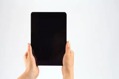 Mãos cortadas de uma pessoa segurando um tablet digital contra um fundo branco