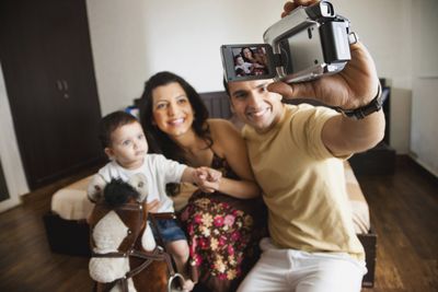 Um homem segurando uma câmera de vídeo voltado para ele e sua família.