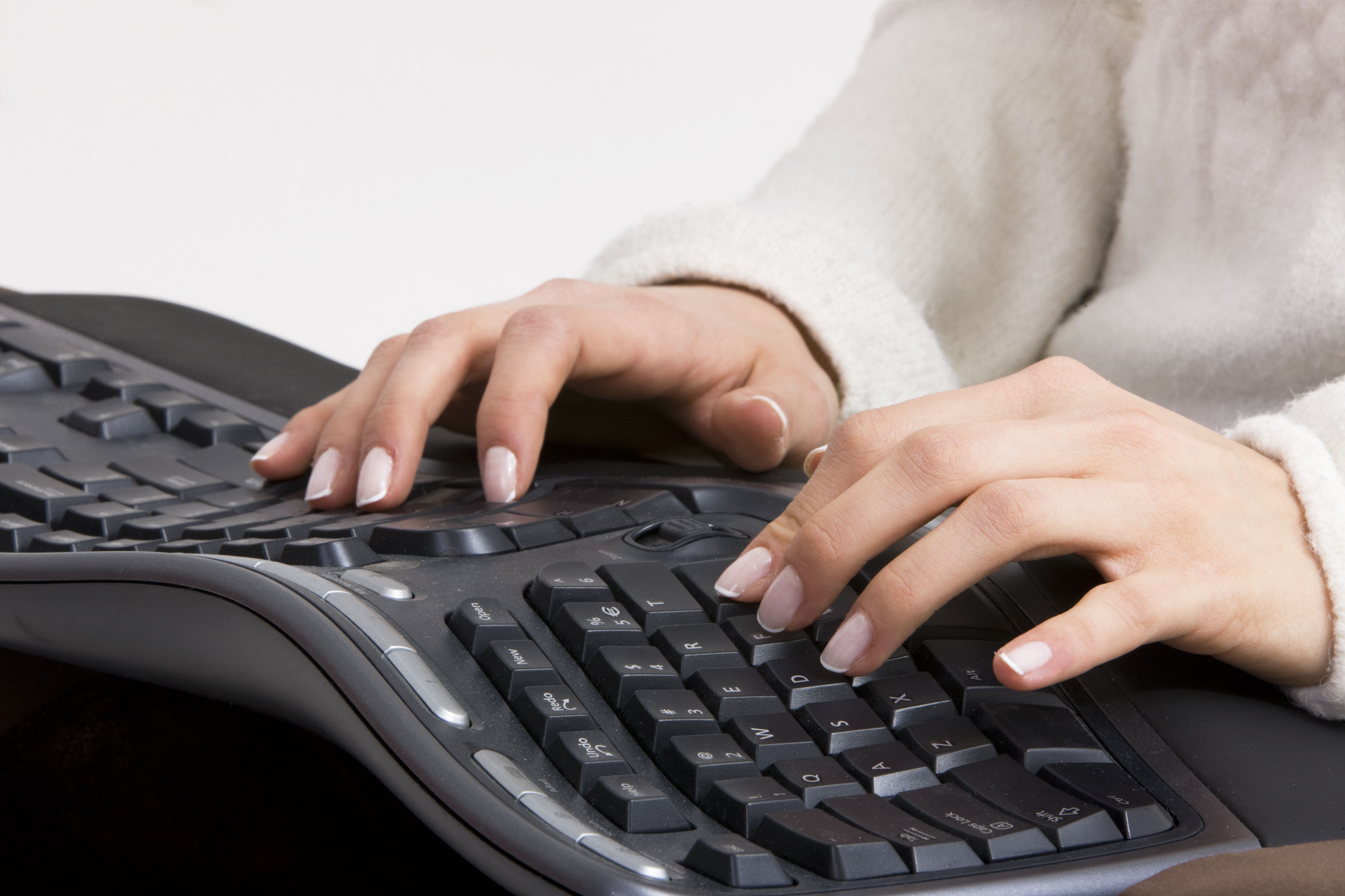 mãos digitando em teclado ergonômico