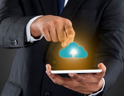 Uma ilustração fotográfica que mostra um homem segurando um smartphone enquanto o desenho de uma nuvem representa o upload de dados do telefone para um armazenamento externo.