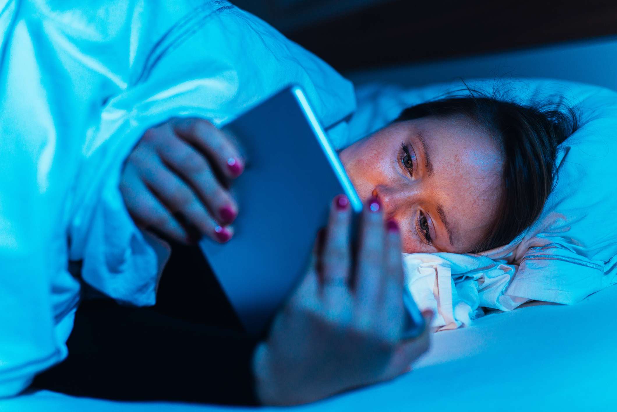 mulher usando seu tablet na cama à noite