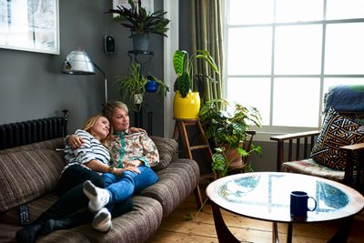 Um casal do mesmo sexo feminino deitado em um sofá assistindo TV