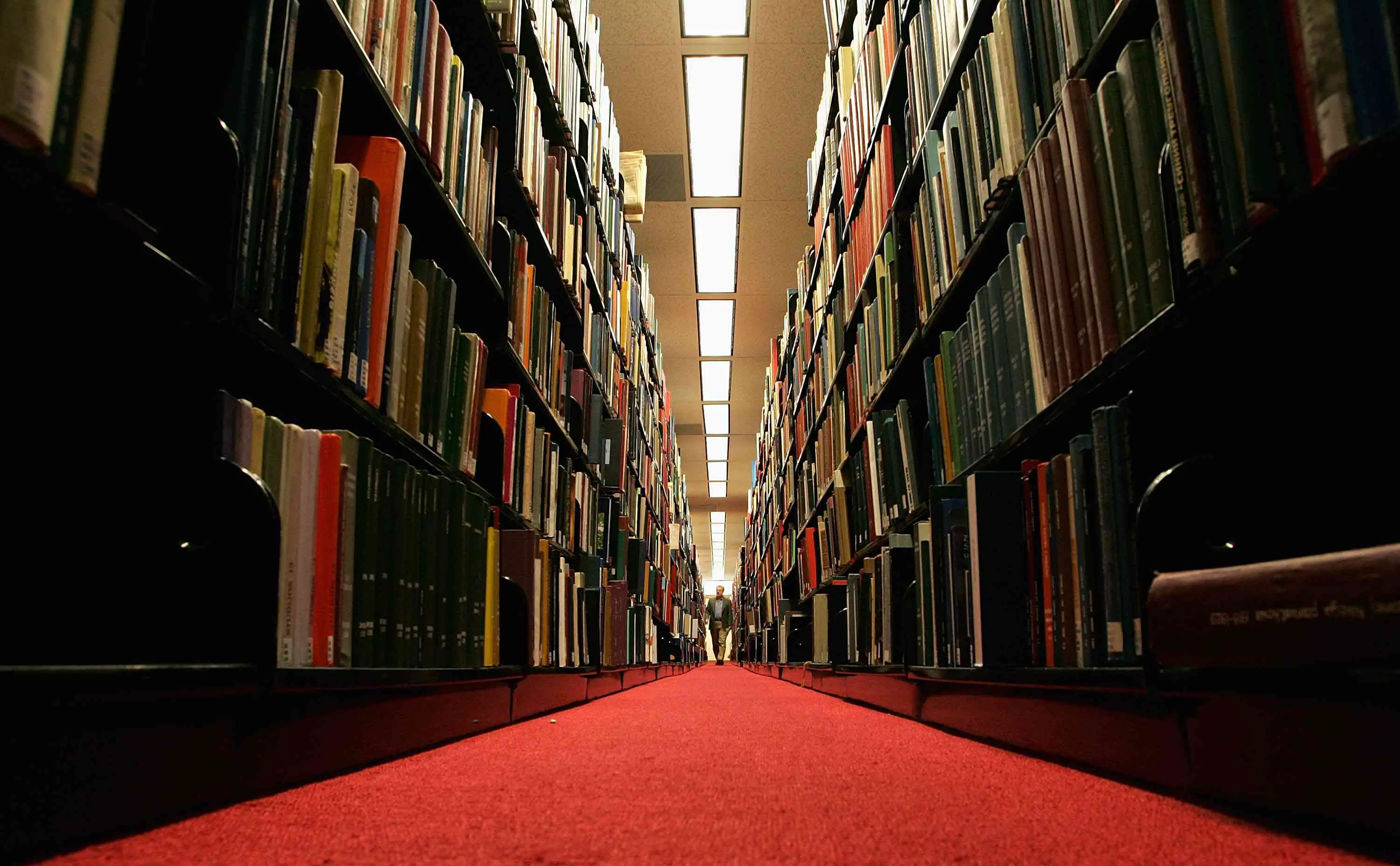 Os livros ocupam o corredor de uma biblioteca, representando as Bibliotecas do Google Livros