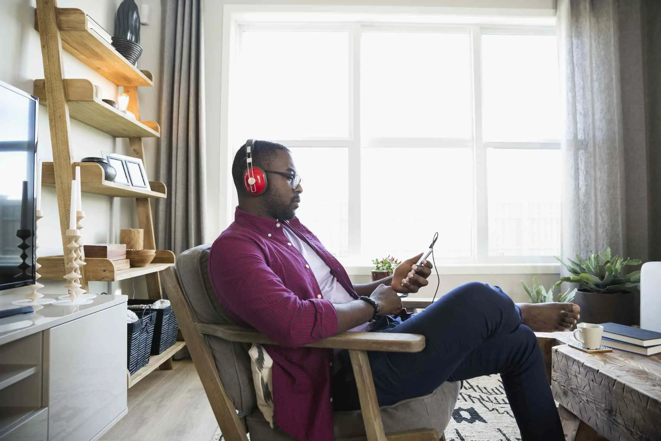 Homem com fones de ouvido e mp3 player ouvindo música na sala de estar