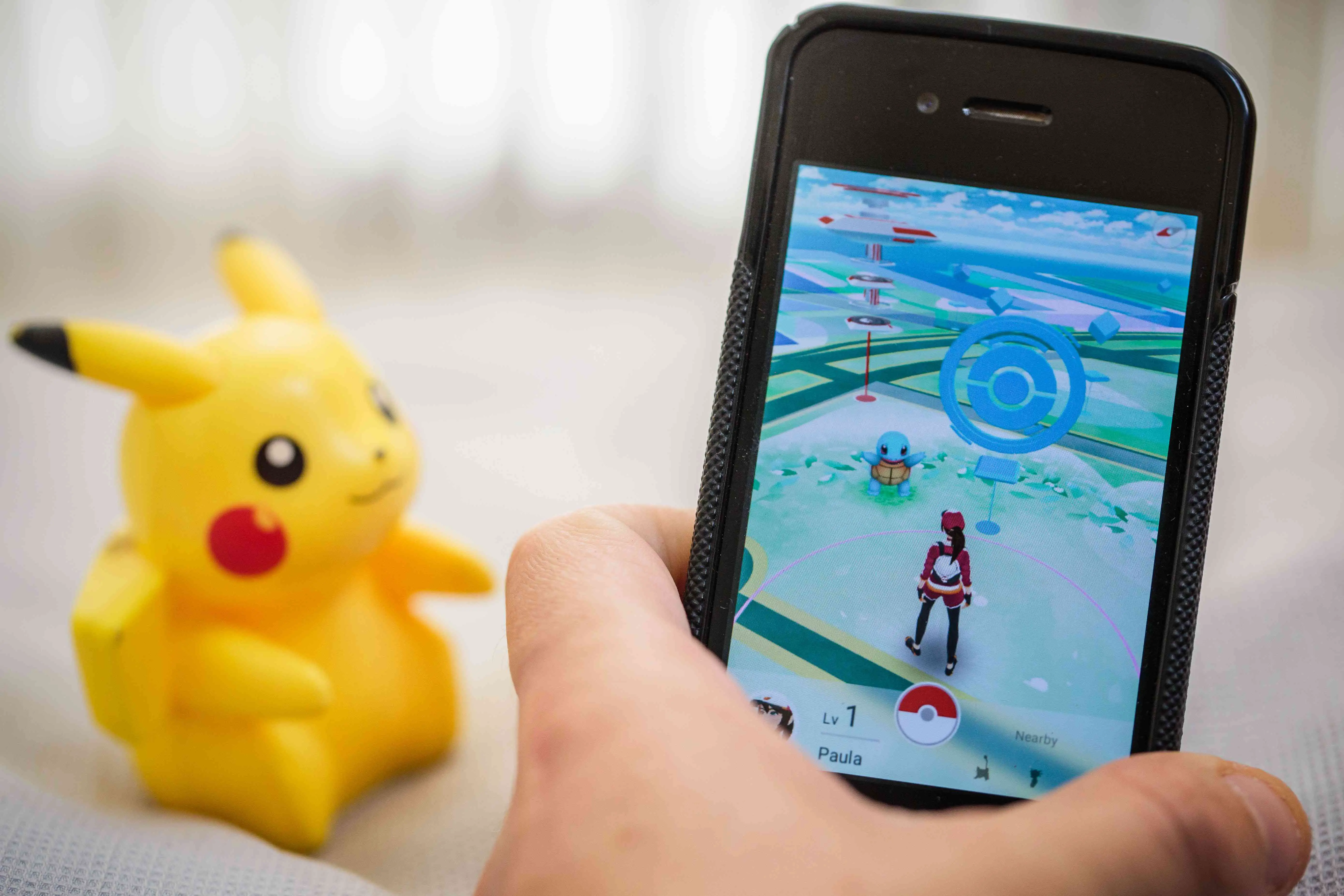 Pokémon Go em um smartphone com um brinquedo Pikachu ao fundo