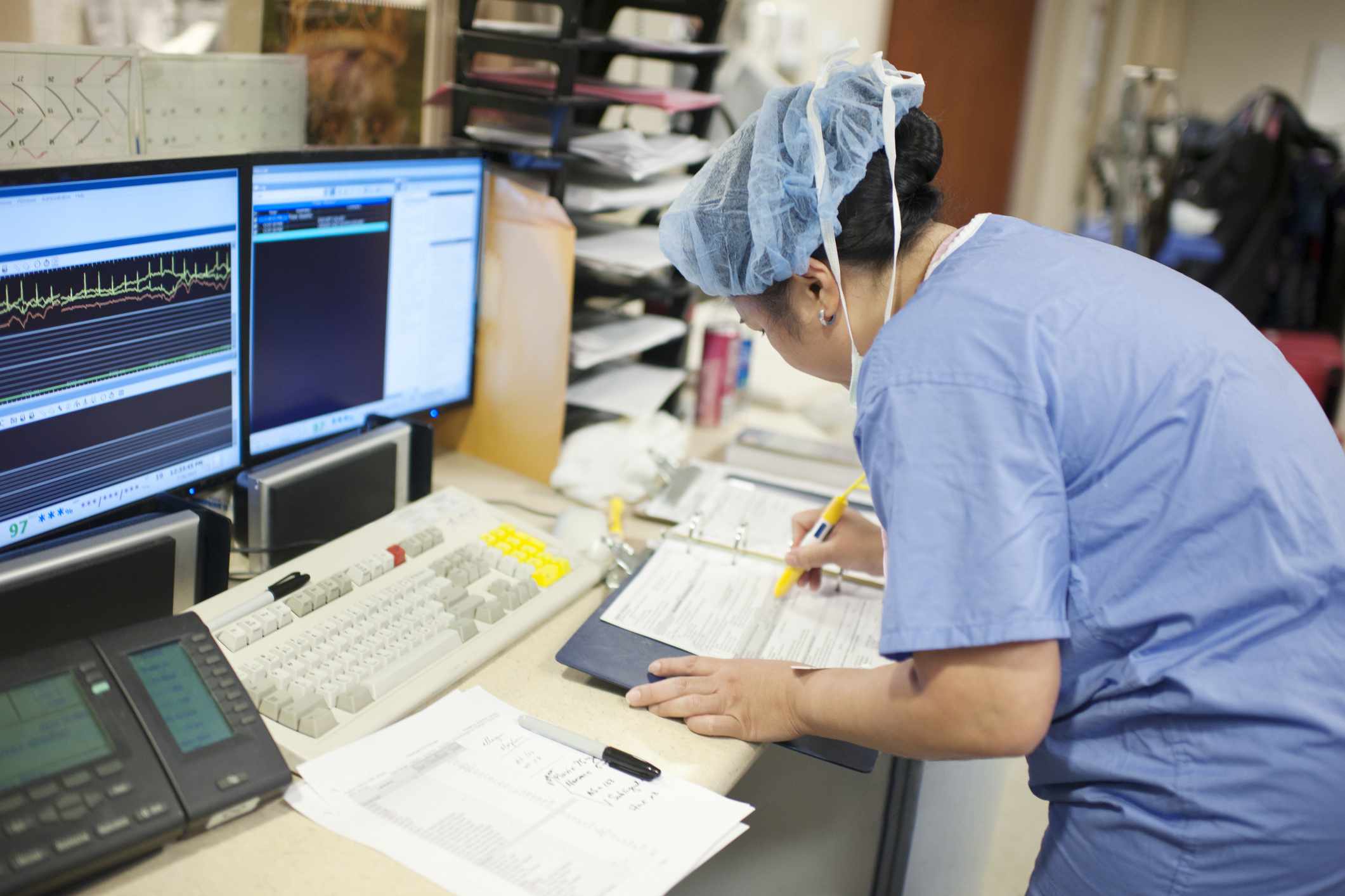 Trabalhador de hospital em frente a duas telas de computador.