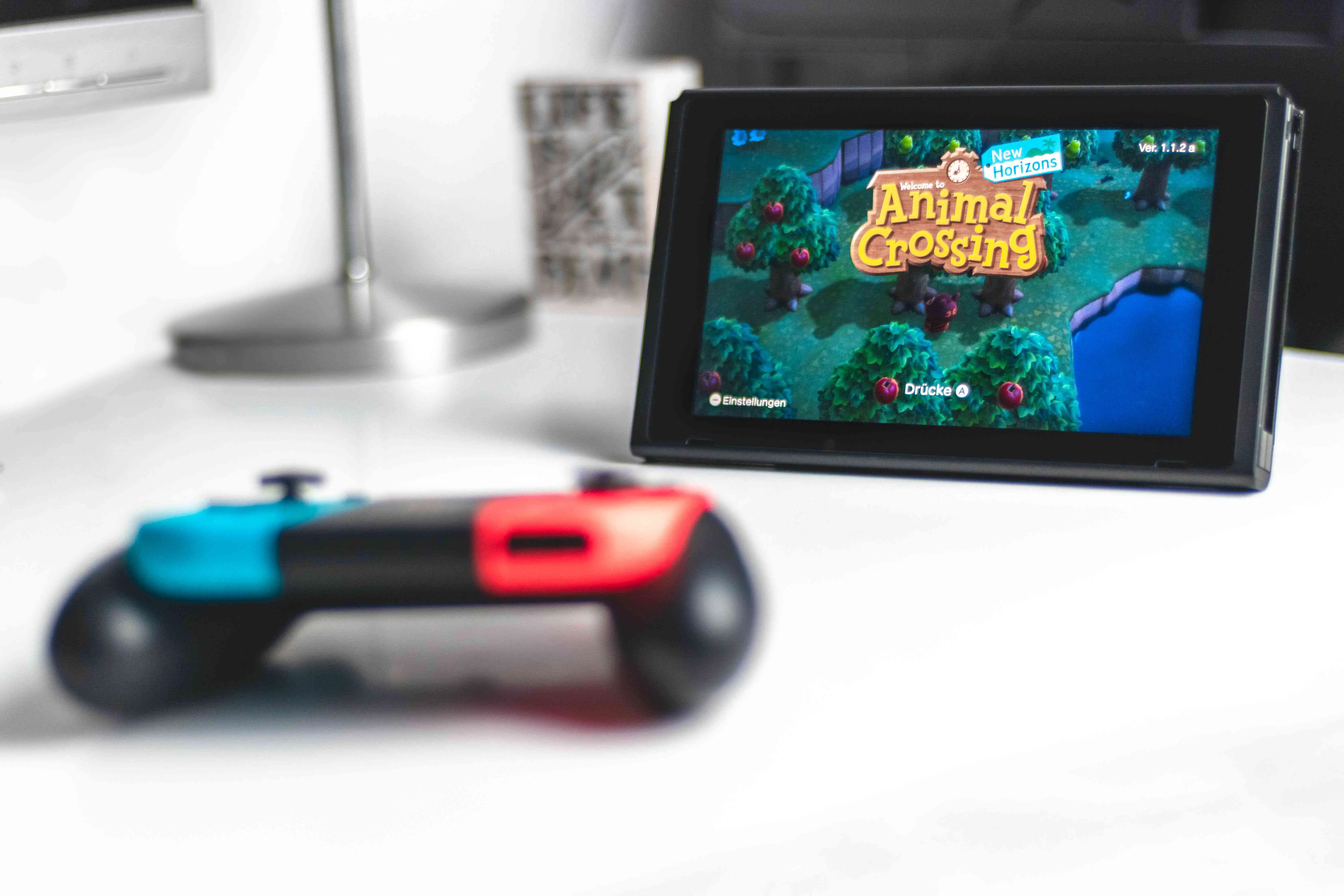 Tablet Nintendo Switch com controlador separado em um fundo branco, Animal Crossing exibido na tela. 